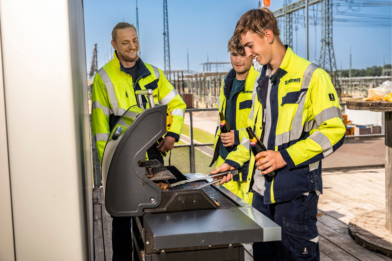 Auszubildende grillen gemeinsam bei einem Teamevent auf dem Firmengelände.