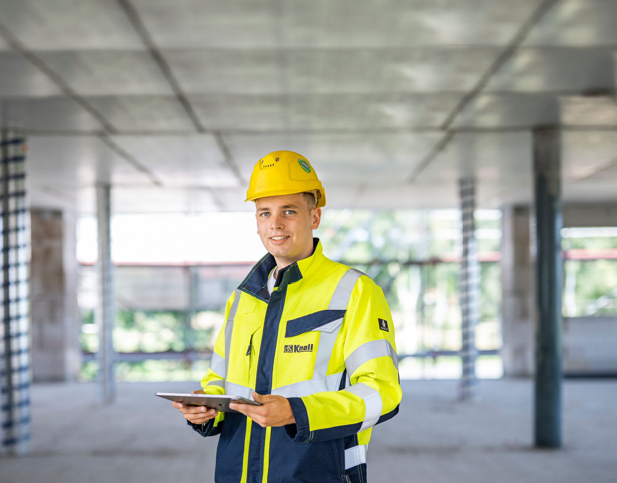 Werkstudent auf einer Baustelle mit Tablet zur digitalen Projektsteuerung.