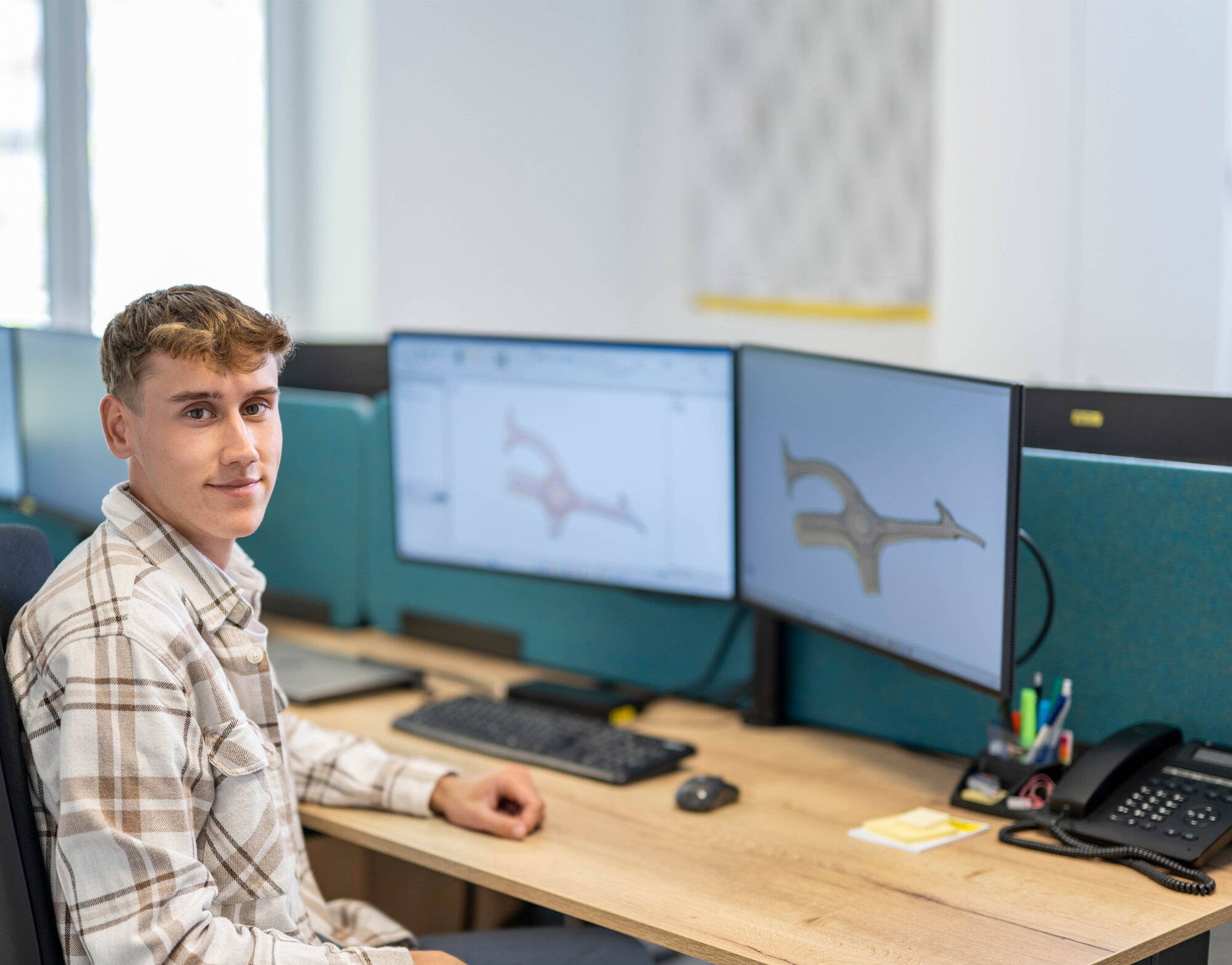 Auszubildender zum Vermessungstechniker arbeitet an einem CAD-Arbeitsplatz mit zwei Monitoren.